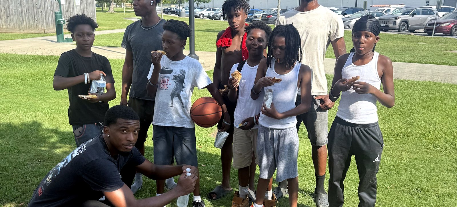A group of kids and RaqGiveback mentors after a pickup basketball game in the park.