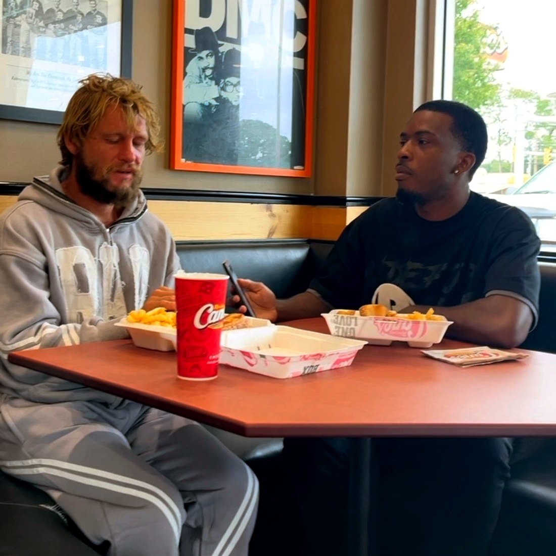A RaqGiveback volunteer sharing a meal and conversation with a community member.