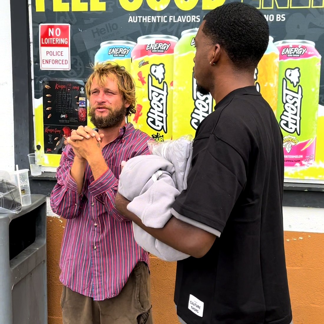 A RaqGiveback volunteer praying with a community member outside a local store.