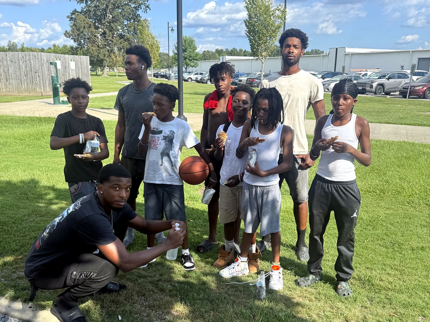 RaqGiveback mentors sharing snacks with kids after a pickup basketball game in the park.