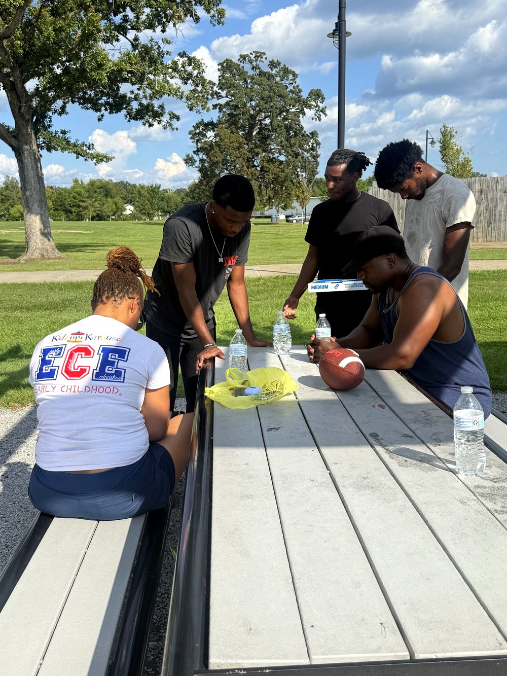 RaqGiveback team members gathered around a picnic table before a community outing.