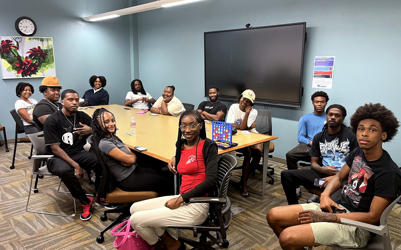 A group of RaqGiveback mentors and mentees meeting around a conference table.